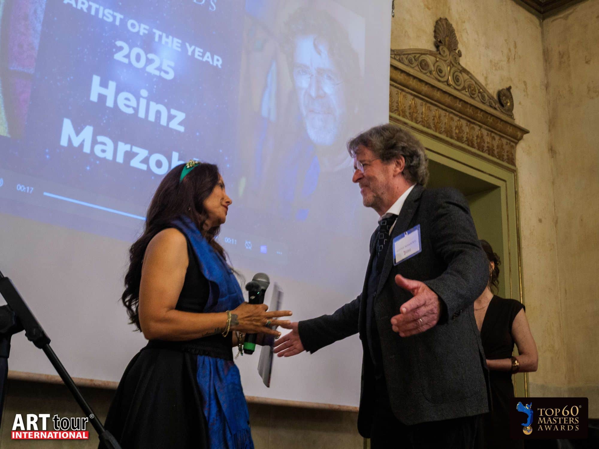 Heinz Marzohl is announced as Artist of the Year 2025 and greeted by Viviana Puello